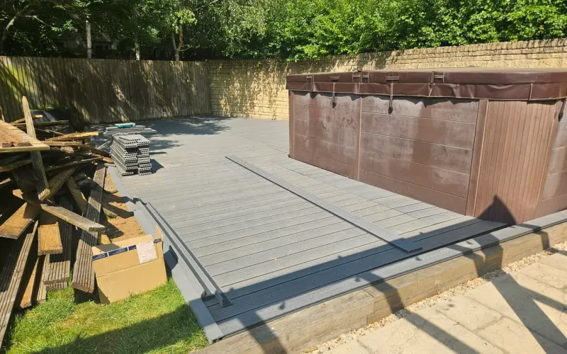Grey composite decking fitted around a hot tub, with tools and spare materials beside the work