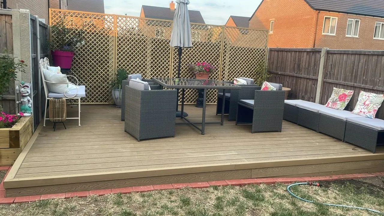 Garden decking with dining furniture, seating and a lattice screen in Carterton