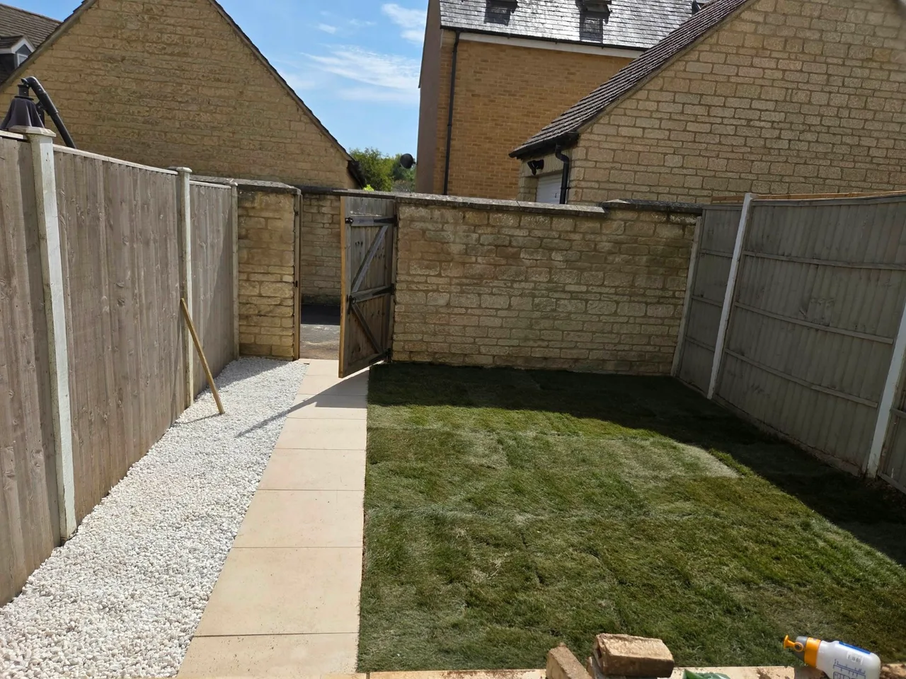 Garden lawn beside a straight paved path and light gravel border in Carterton
