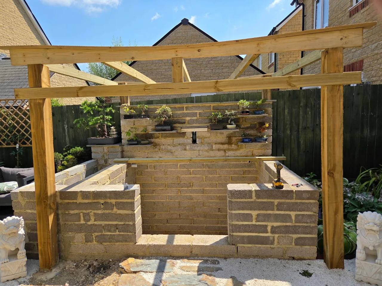 Timber pergola frame surrounding garden blockwork under construction in Carterton