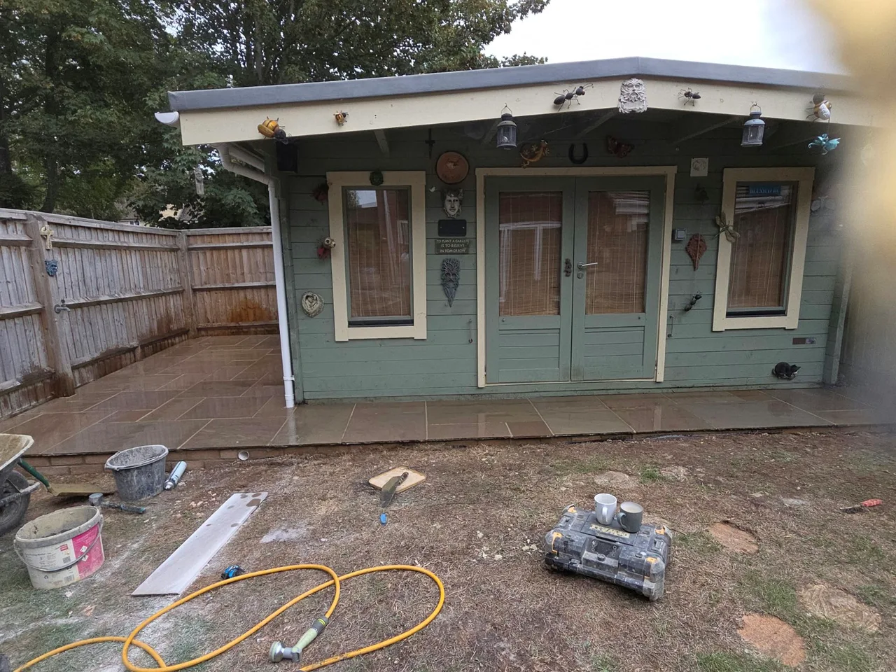 Paving across the front and side of a painted garden summerhouse in Carterton