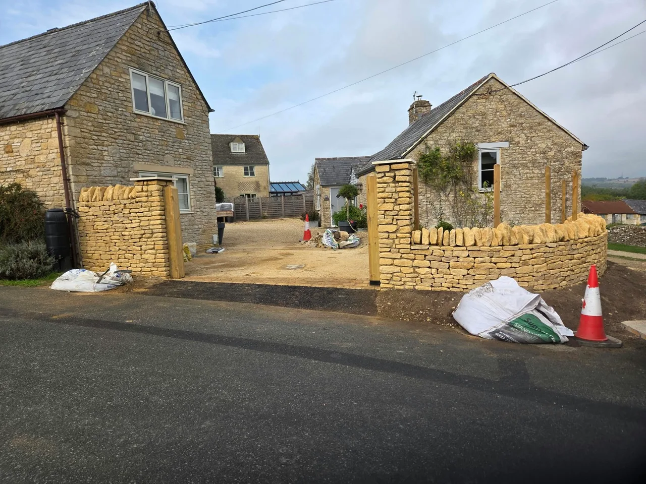 Curved stone entrance wall with upright coping and stone piers in Nether Westcote